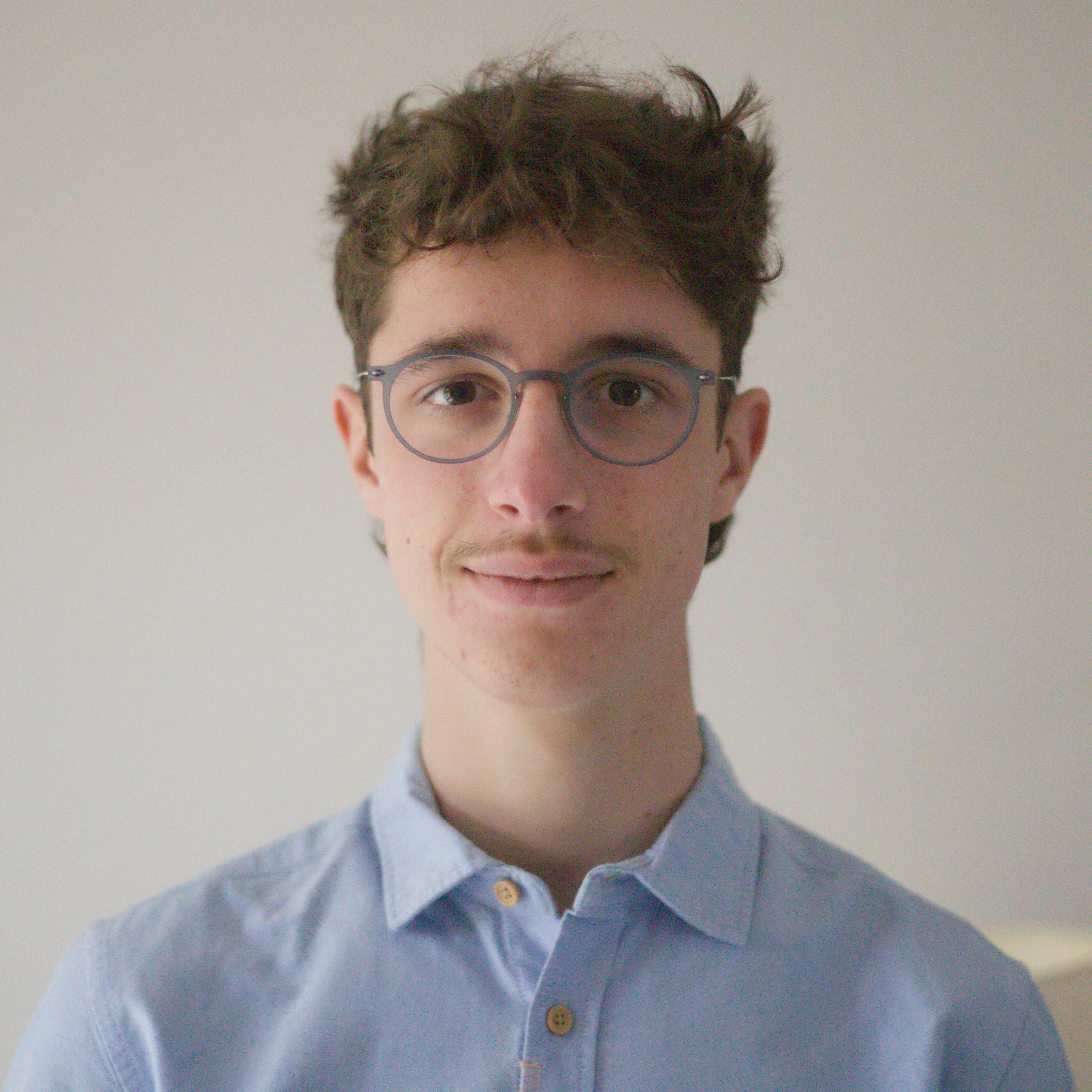 Photo of Antonin. He's looking straight at the camera, wears a blue shirt and is smiling